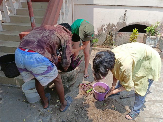 Community young man and Japanese students from ICU planting flowers and recomposing plants pots as part of the homestays in Keta Kedzikorpe